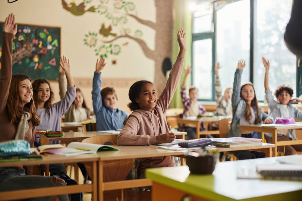 kids raising their hands in a classroom